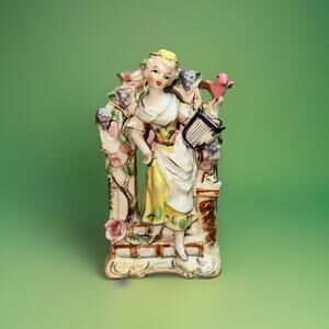Vintage porcelain figurine of a young woman with a lyre under a floral arbor
